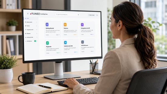 Business customer reviewing the Fundz knowledge base on her office computer to access onboarding, features, integrations, playbooks, and API resources.