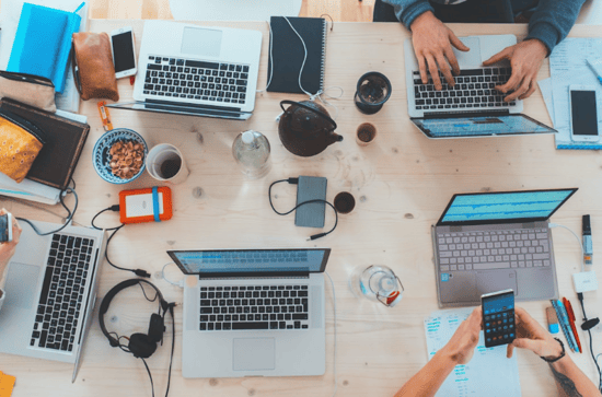 A group of individuals collaborating at a table, each using laptops, focused on integrating newsletter software with marketing platforms.